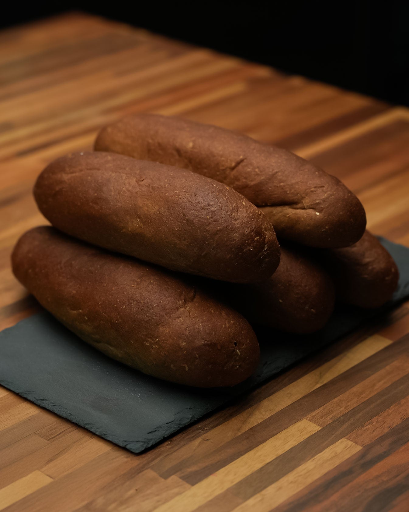 Macromize Samoon Bread stacked on a slate board, showcasing its dark crust and dense texture. High-protein, sugar-free, and keto-friendly.